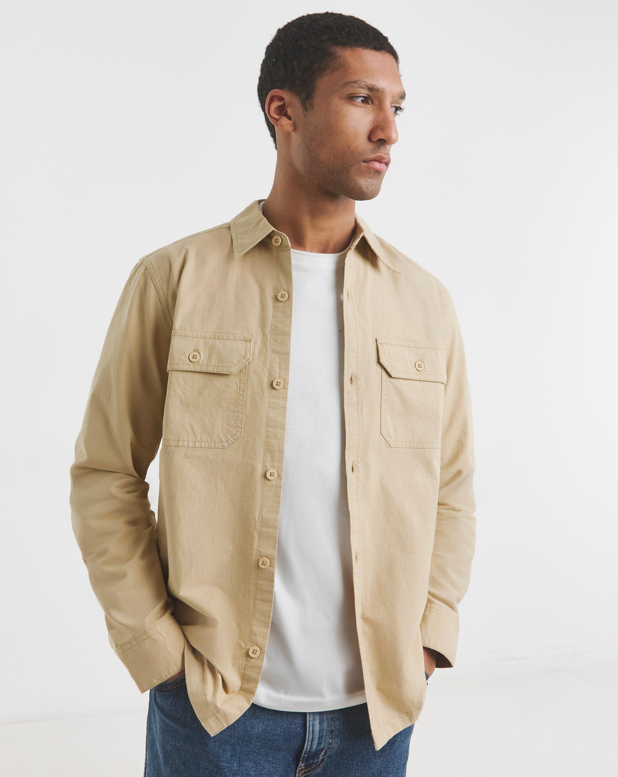 A model wearing a stone-coloured shirt over a white t-shirt